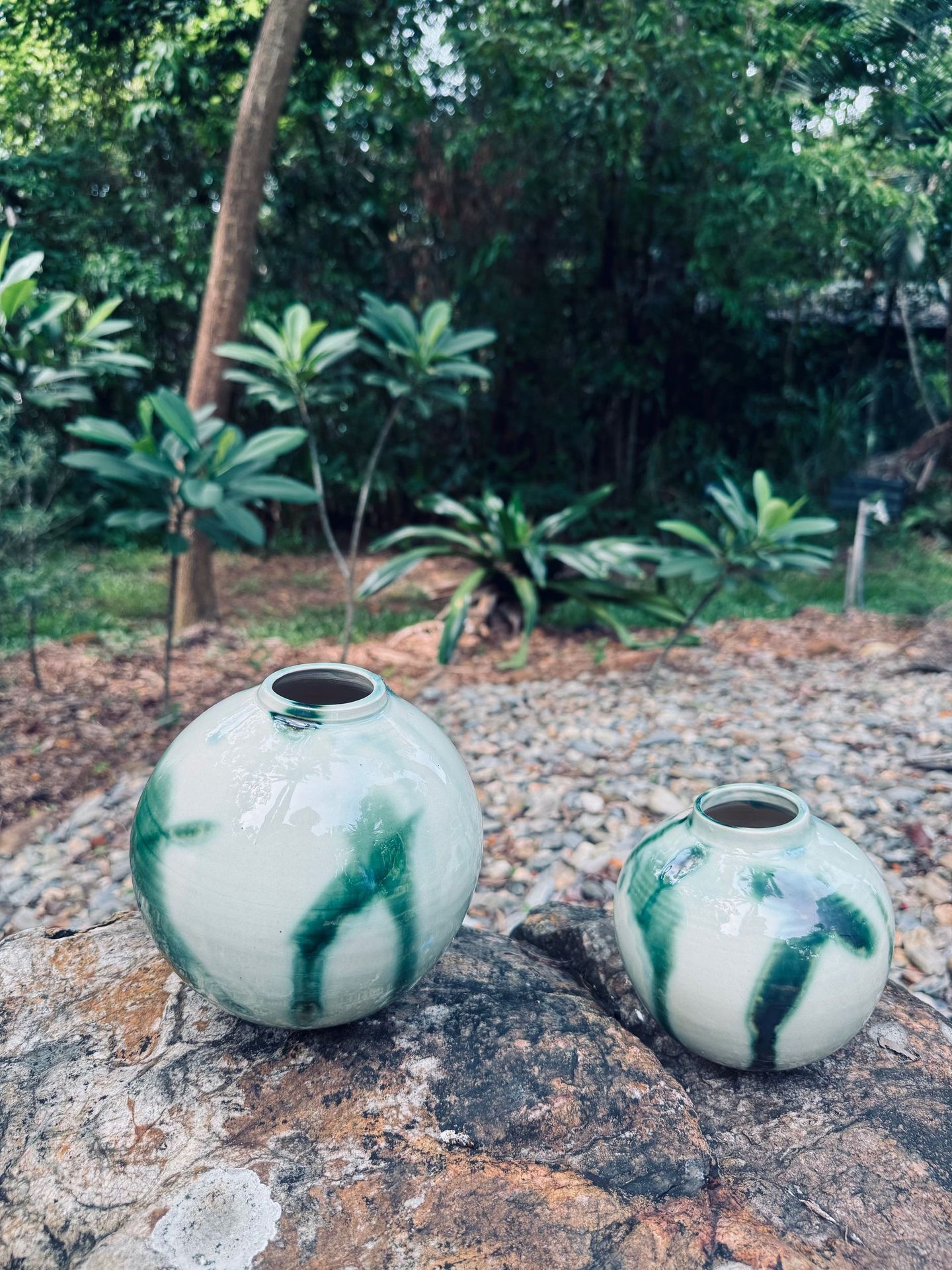 Two green and white vases are sitting on a rock.