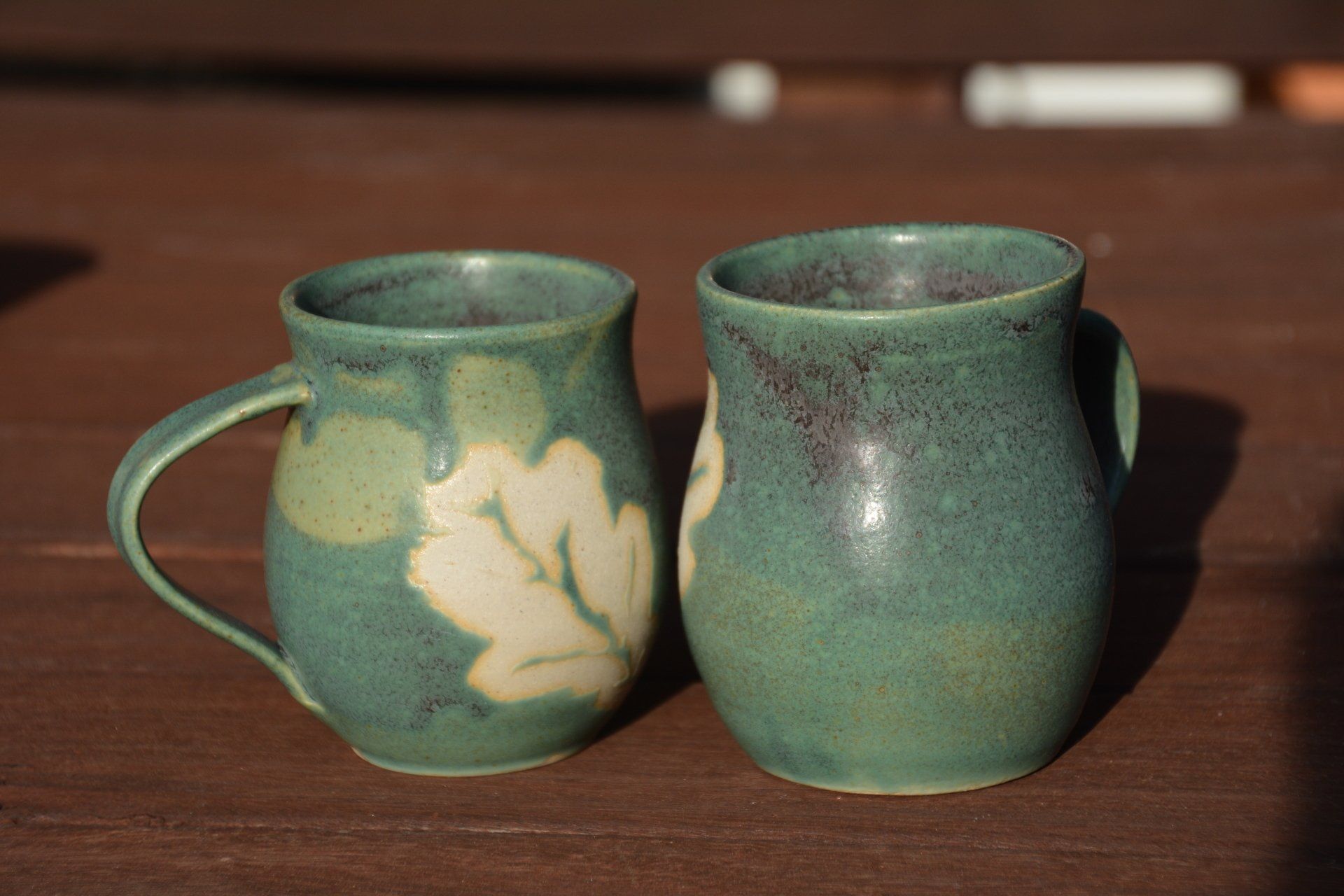Two green mugs are sitting on a wooden table.