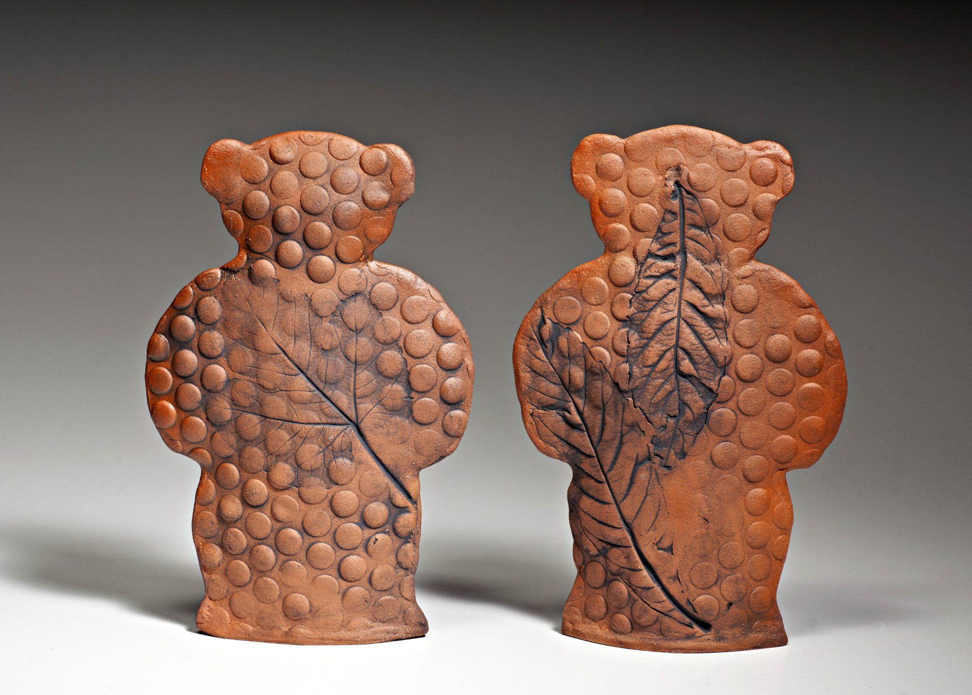 Two brown teddy bears with leaves carved into them
