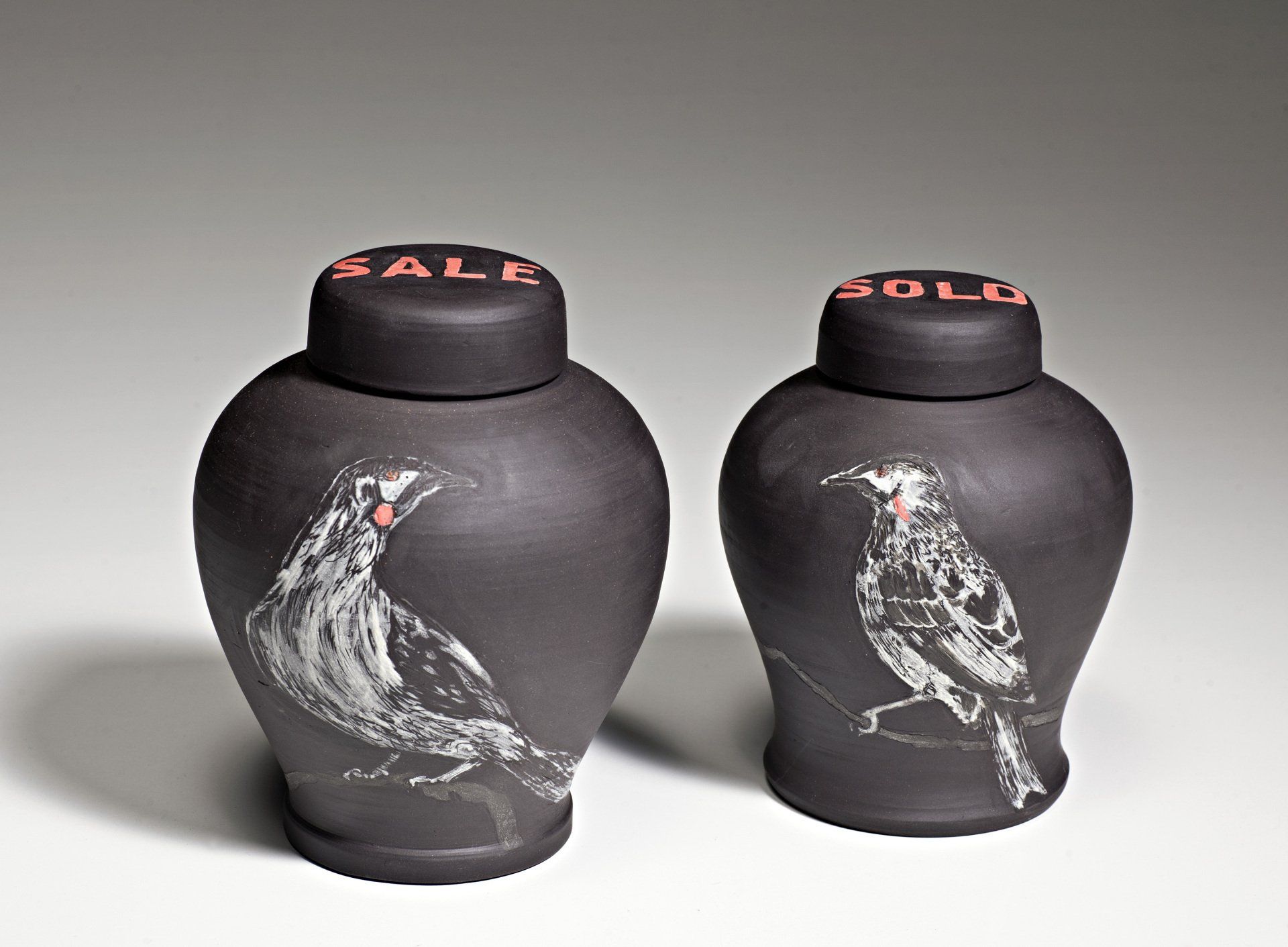 Two black vases with birds painted on them and the word sale on the top