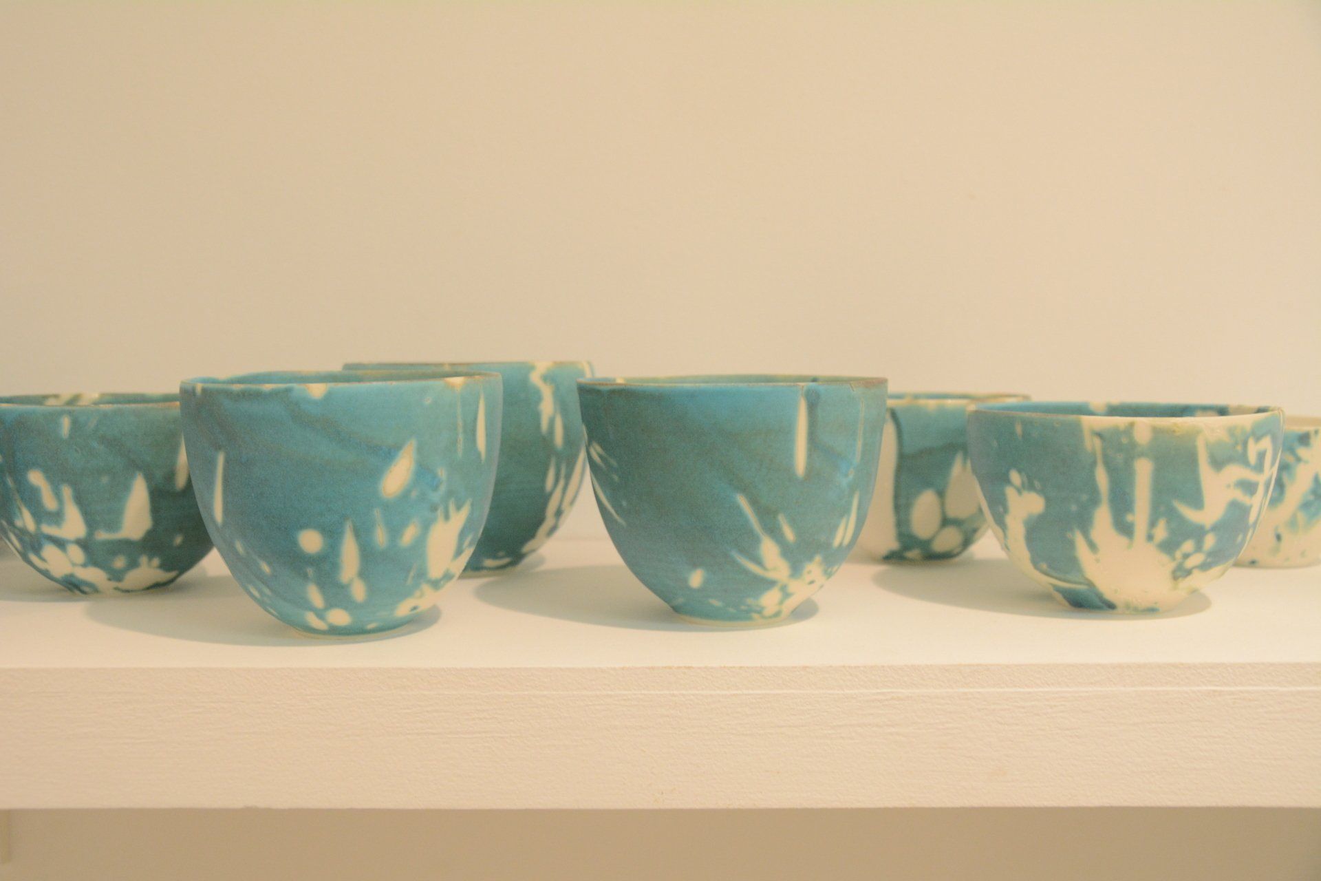 A row of blue and white bowls are sitting on a white shelf.