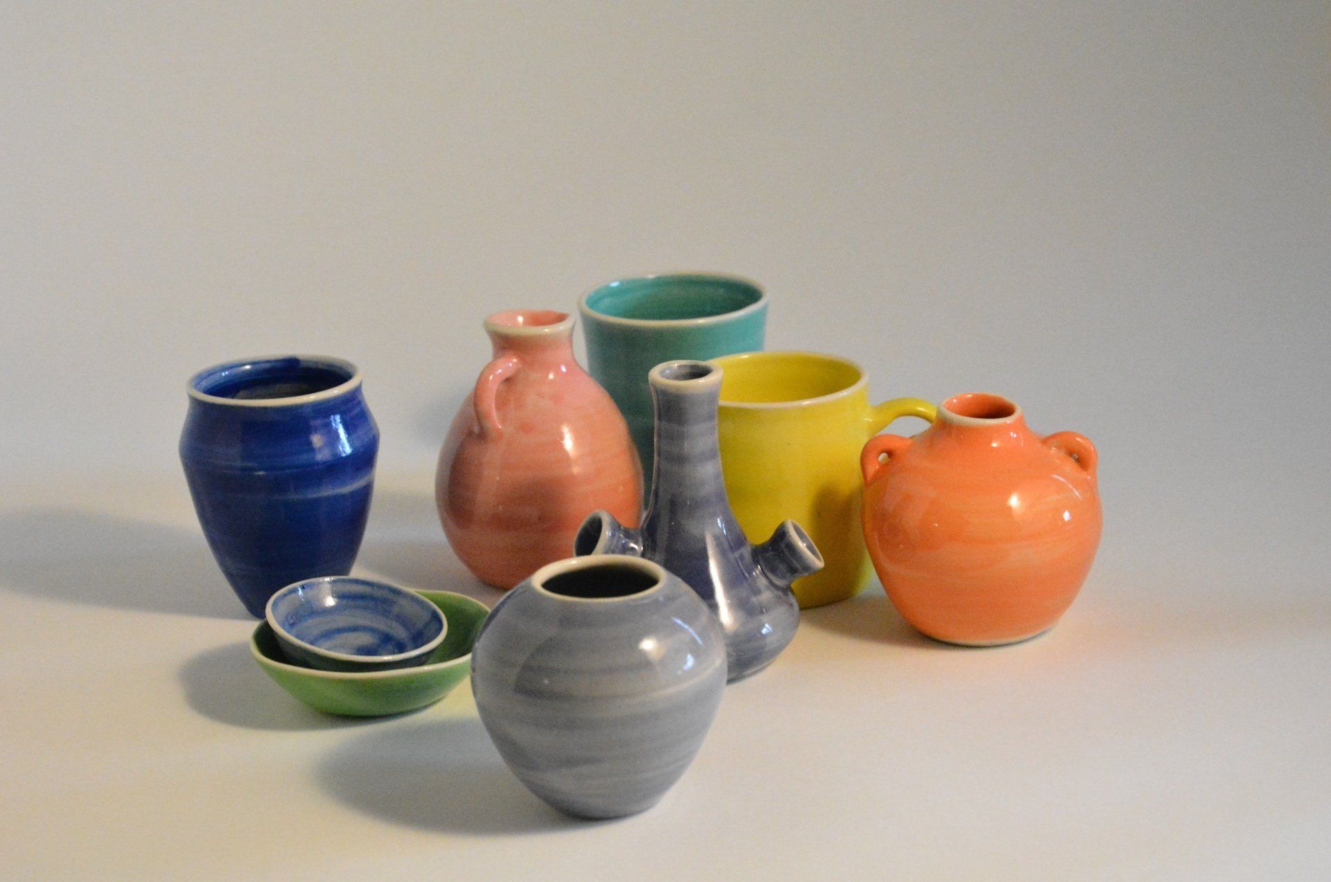 A group of colorful vases and bowls are sitting on a table.