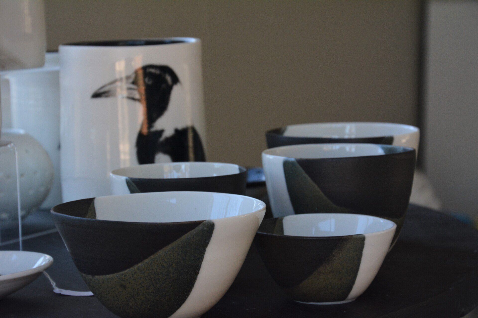 Black and white bowls on a table with a vase with a bird on it