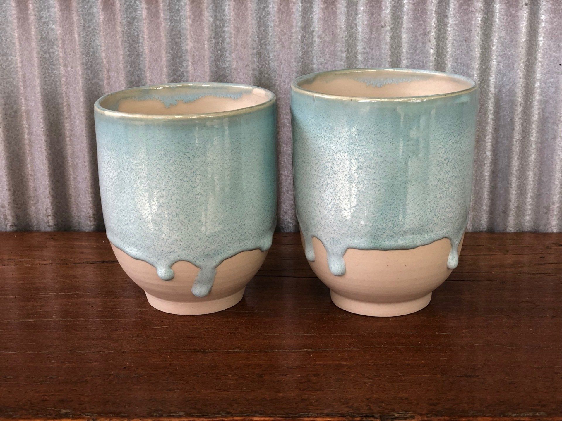 Two ceramic cups are sitting on a wooden table.