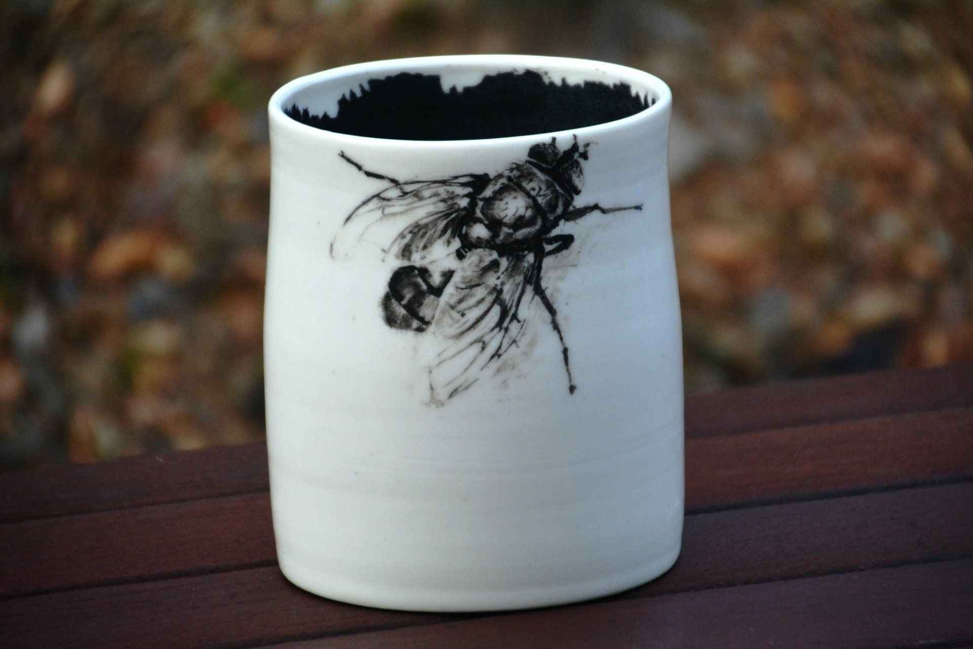 A white vase with a black bee on it
