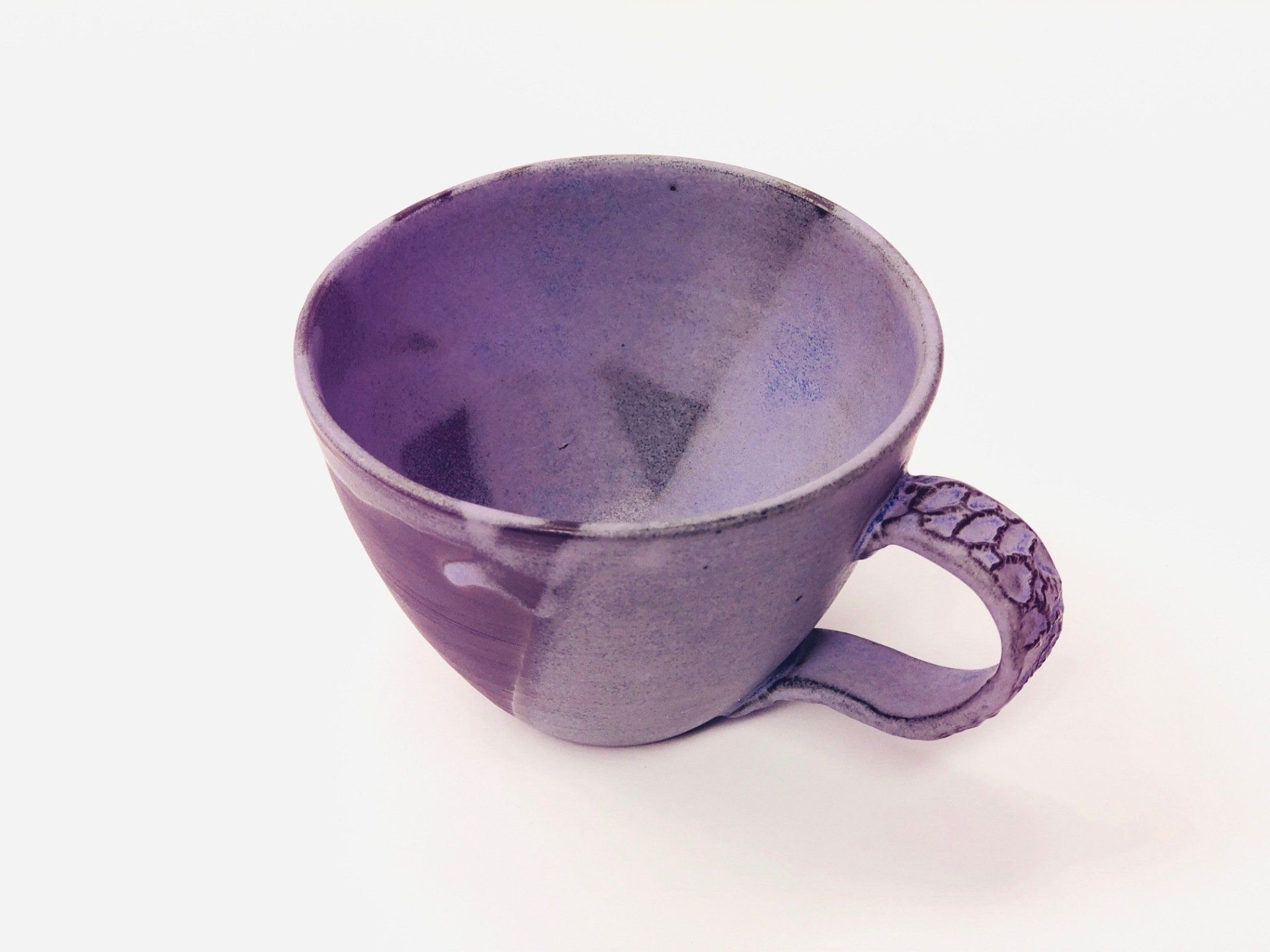 A purple cup with a handle on a white background