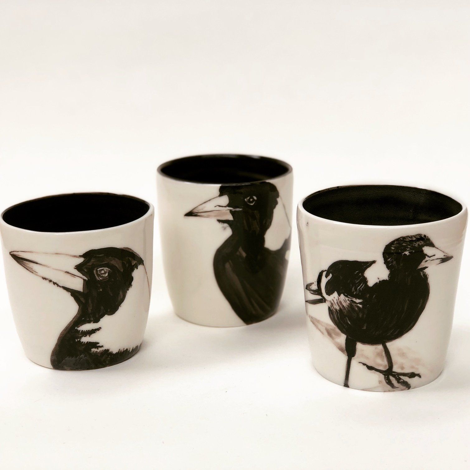 Three cups with black and white birds on them