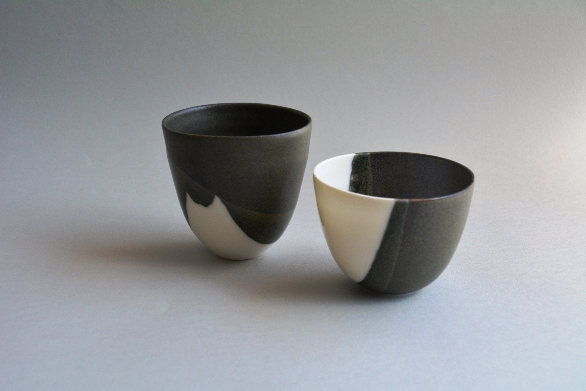 Two black and white cups are sitting on a table.