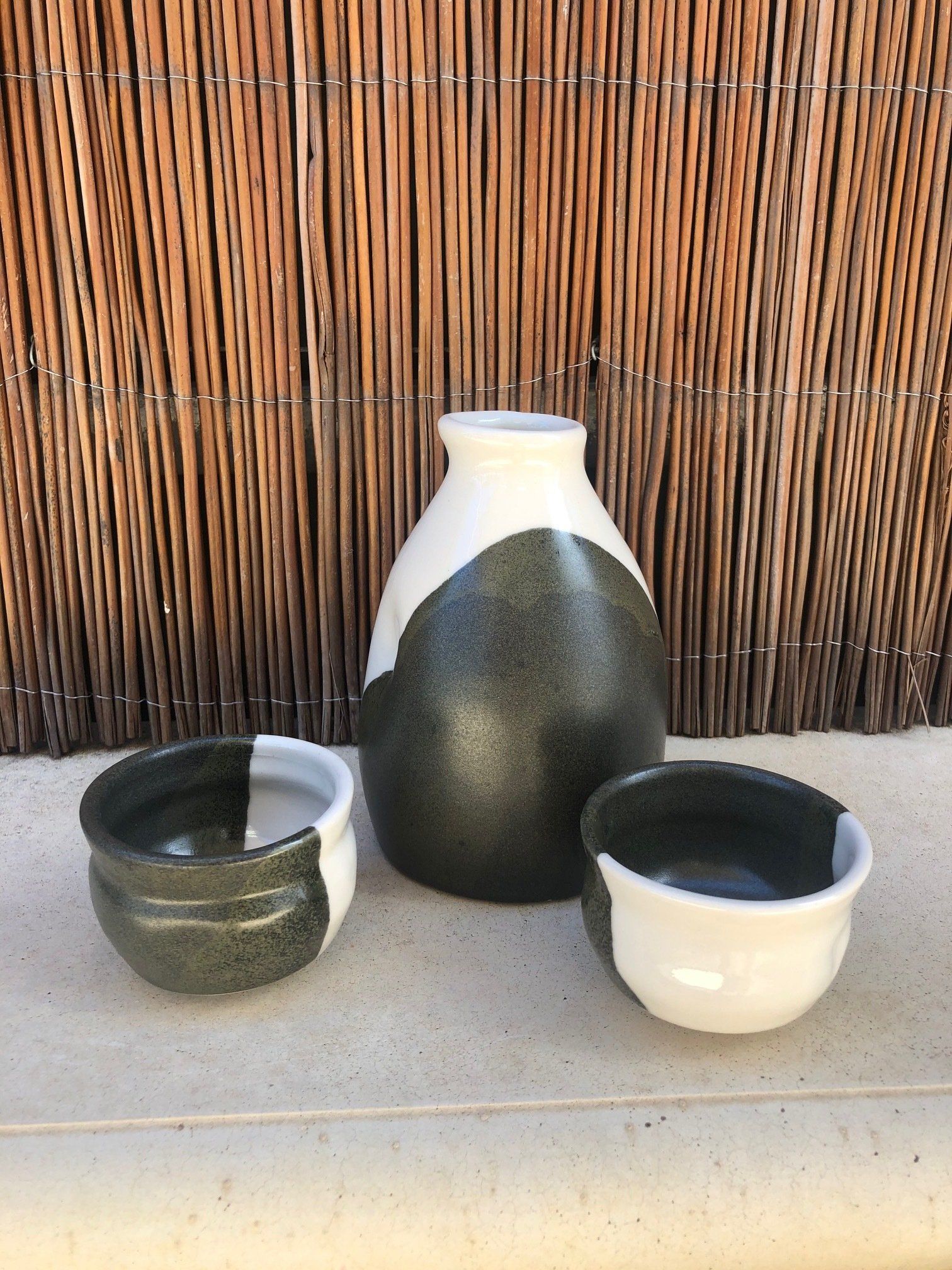 A black and white vase and two bowls are sitting on a table.