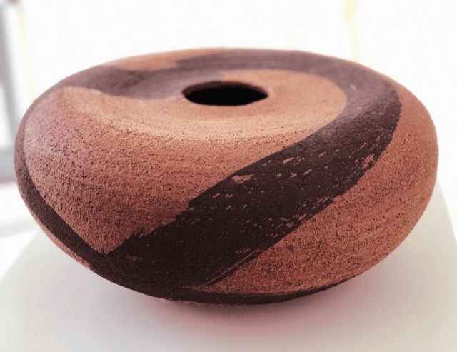 A brown and black ceramic bowl with a hole in the middle