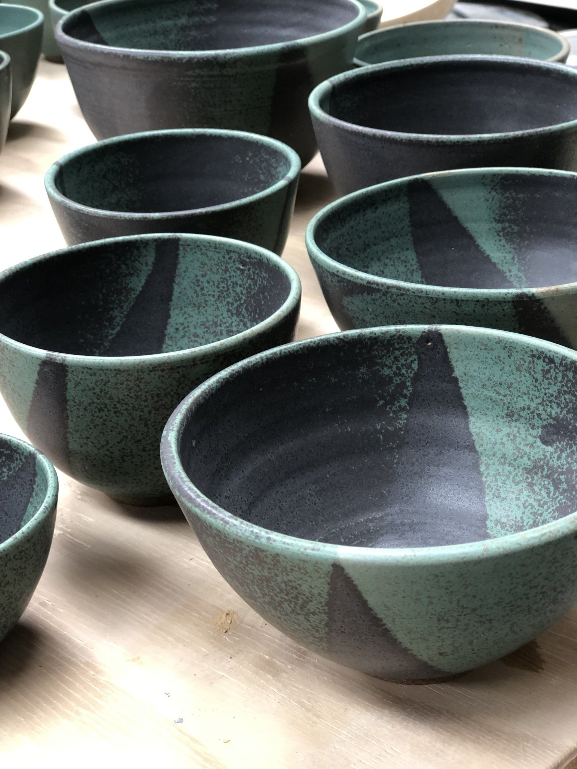 A group of green and black bowls are sitting on a wooden table.
