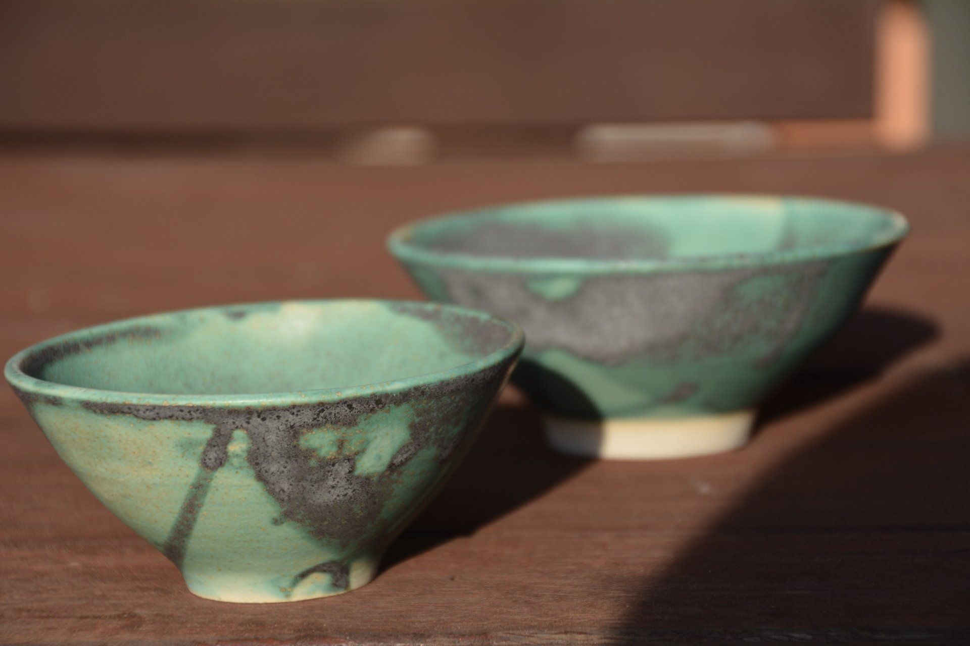 Two green bowls are sitting on a wooden table
