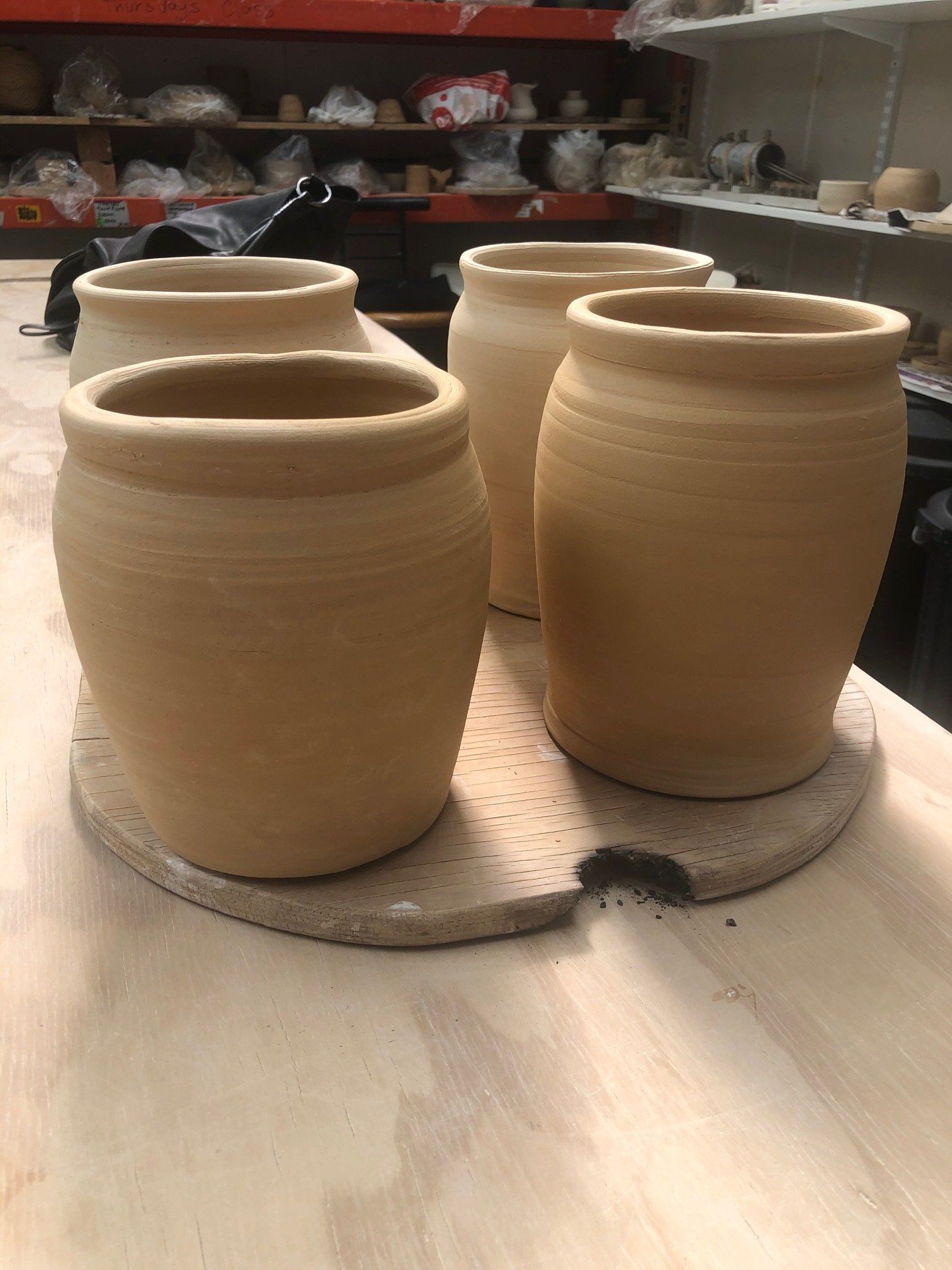 Four clay pots are sitting on a wooden table.