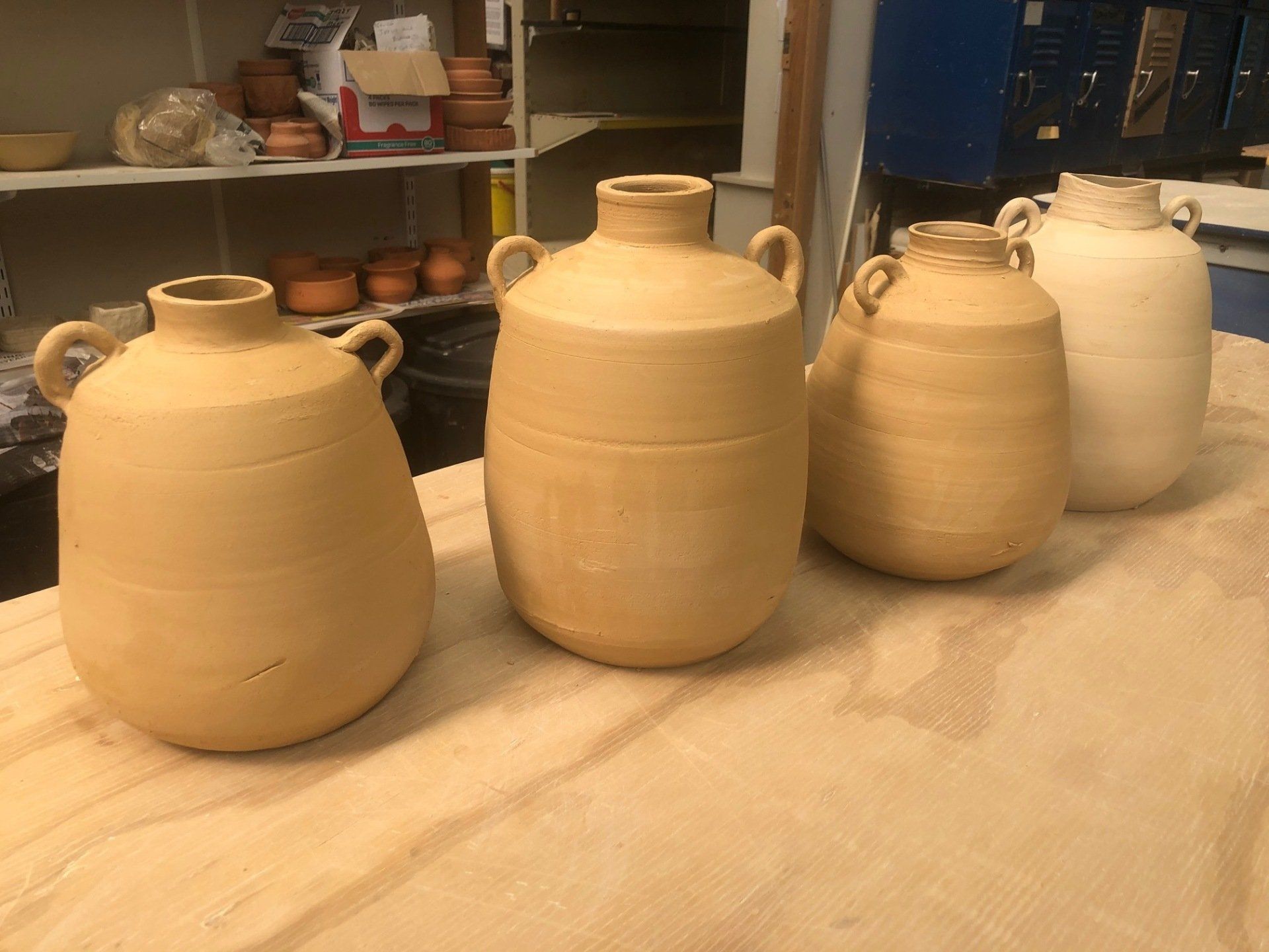A row of clay vases sitting on top of a wooden table.
