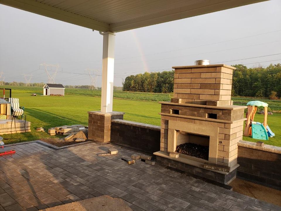 a patio with a fireplace and a rainbow in the background .