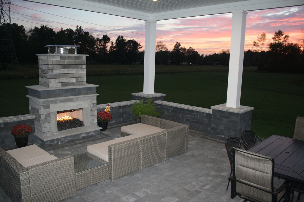 a patio with a fireplace and a sunset in the background