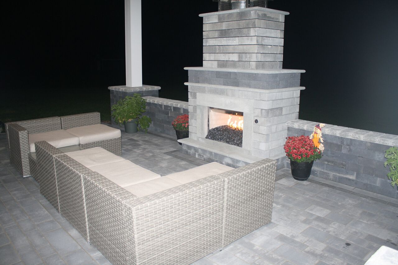 a patio with a fireplace and a couch at night
