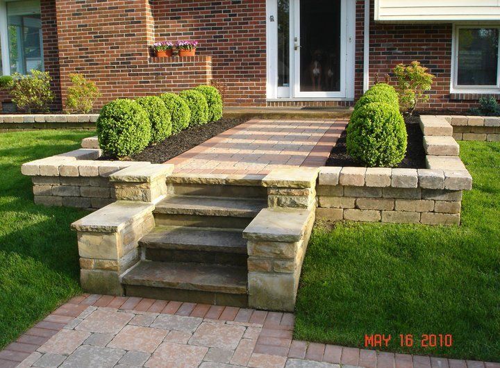 a brick walkway with steps leading up to the front door of a brick house