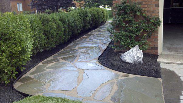 a stone walkway leading to a house with a rock in the middle .