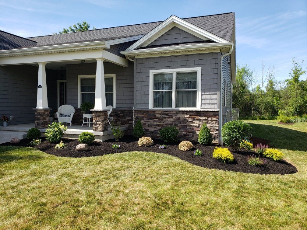 a house with a porch and a lush green lawn in front of it .