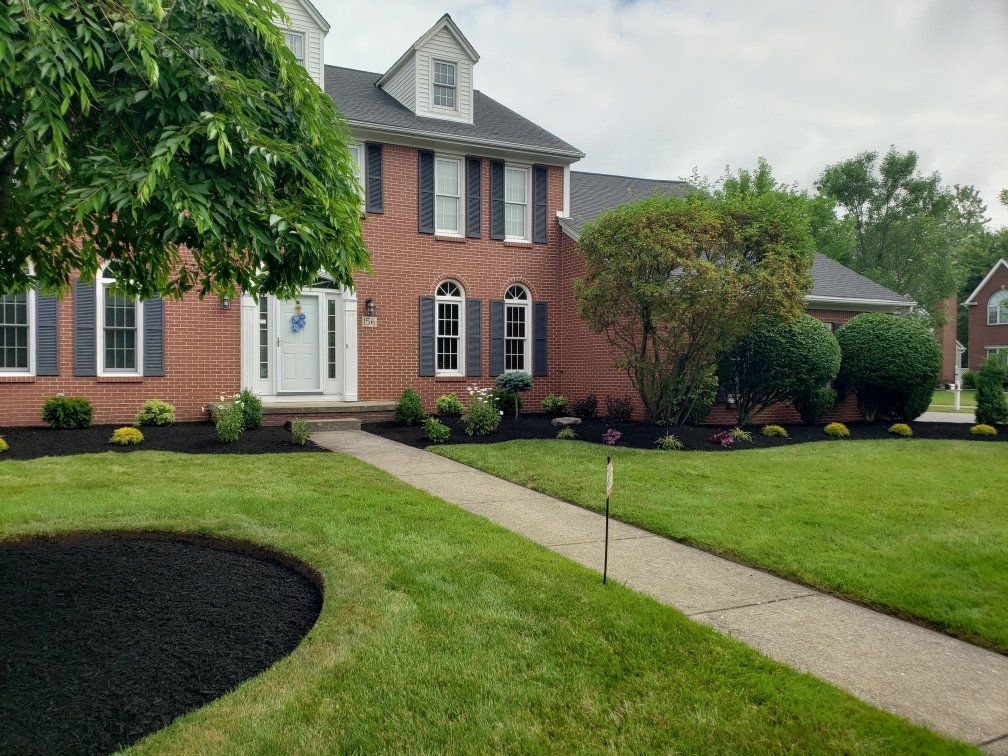 a large brick house with a lush green lawn and a tree in front of it .