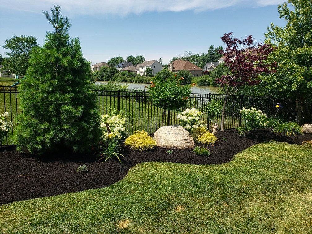 a lush green yard with a fence and a lake in the background