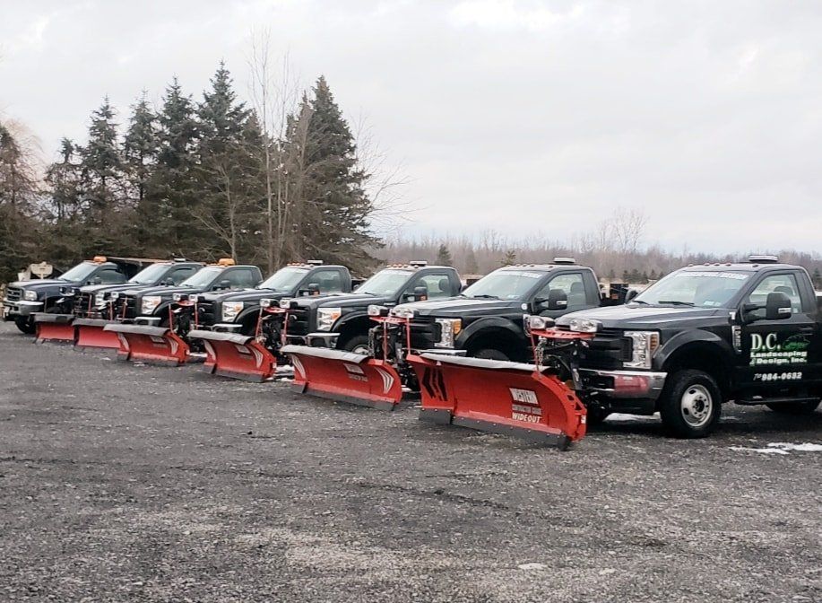 a row of snow plows are parked in a parking lot .