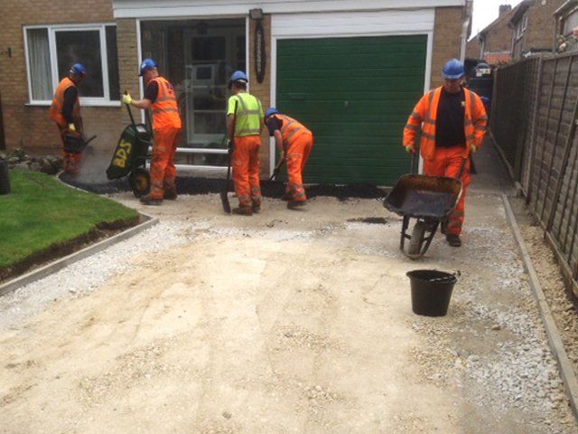 Workers laying a driveway outside a home