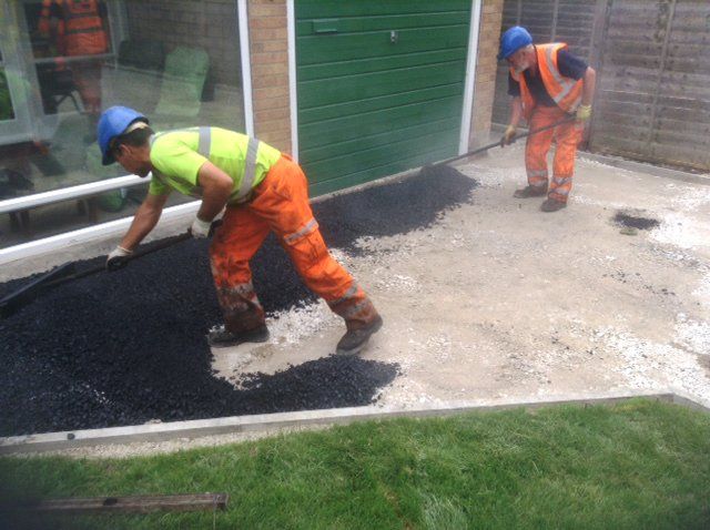 Workers spreading asphalt for a garden path