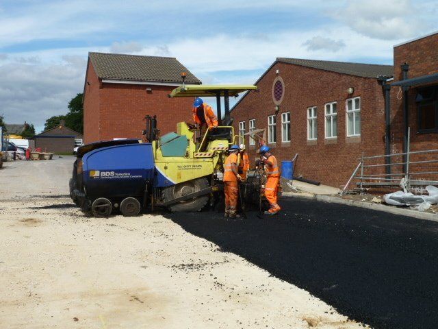 Workers spreading asphalt in a car park