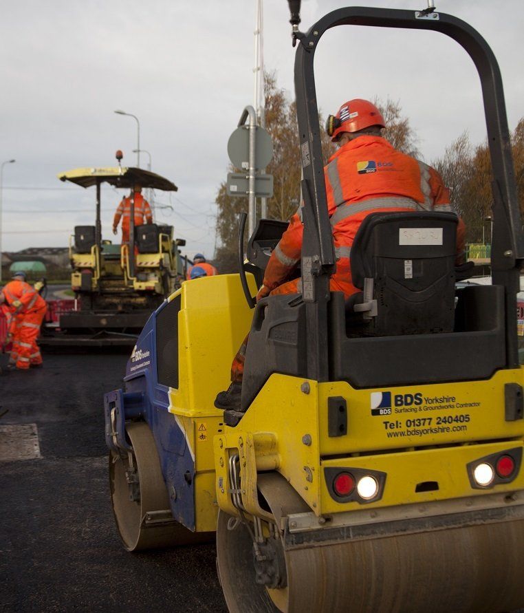 Several items of plant machinery laying a road