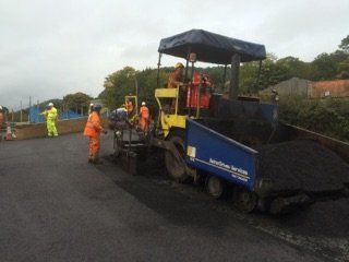 Workers laying asphalt from a trailer
