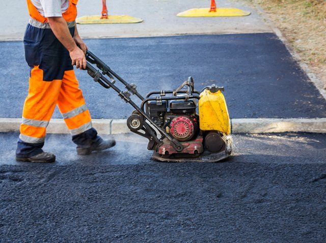 Worker using a portable machine to smooth the surface of a new road