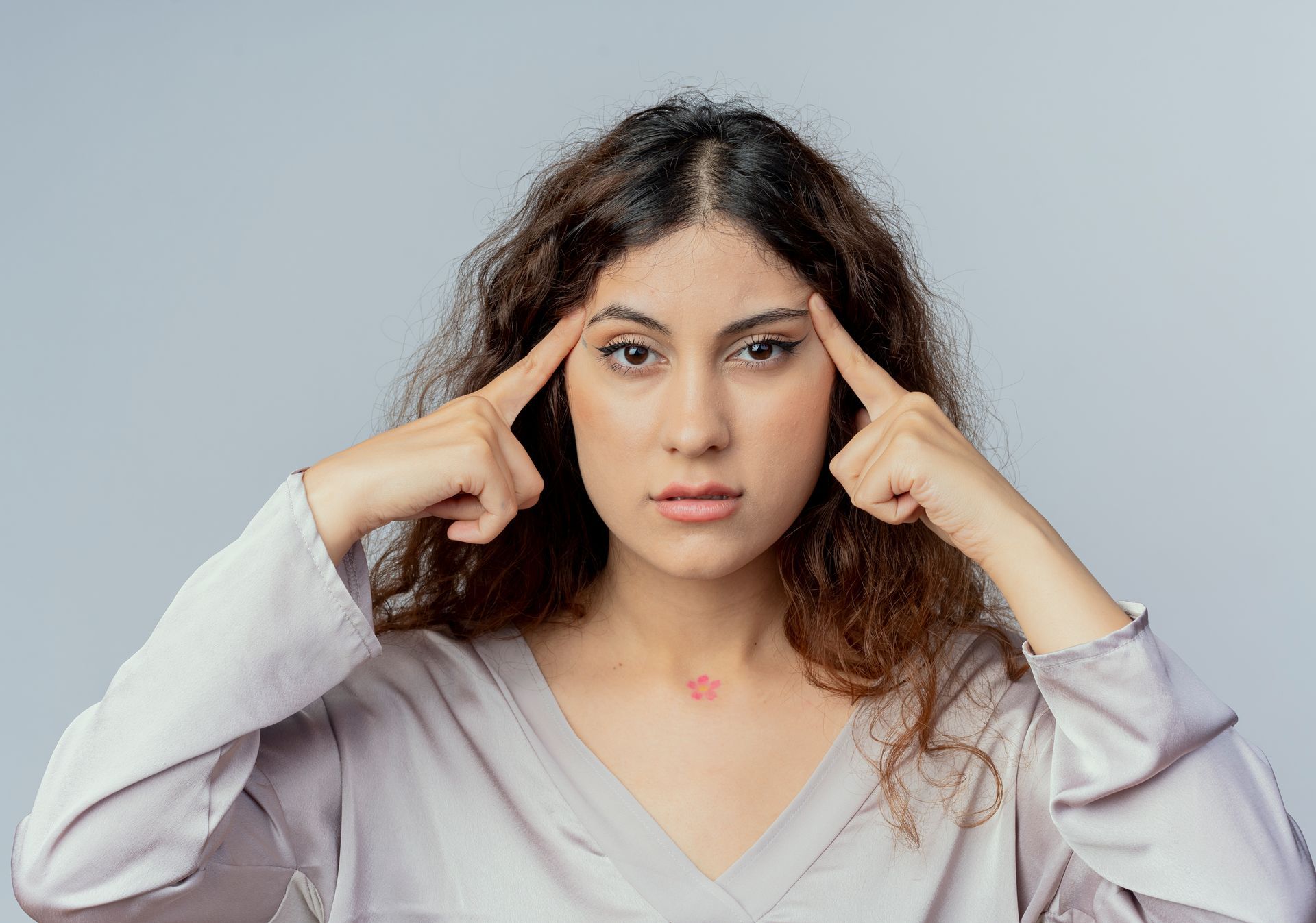 Woman touching temples, looking directly at the viewer with a thoughtful expression.