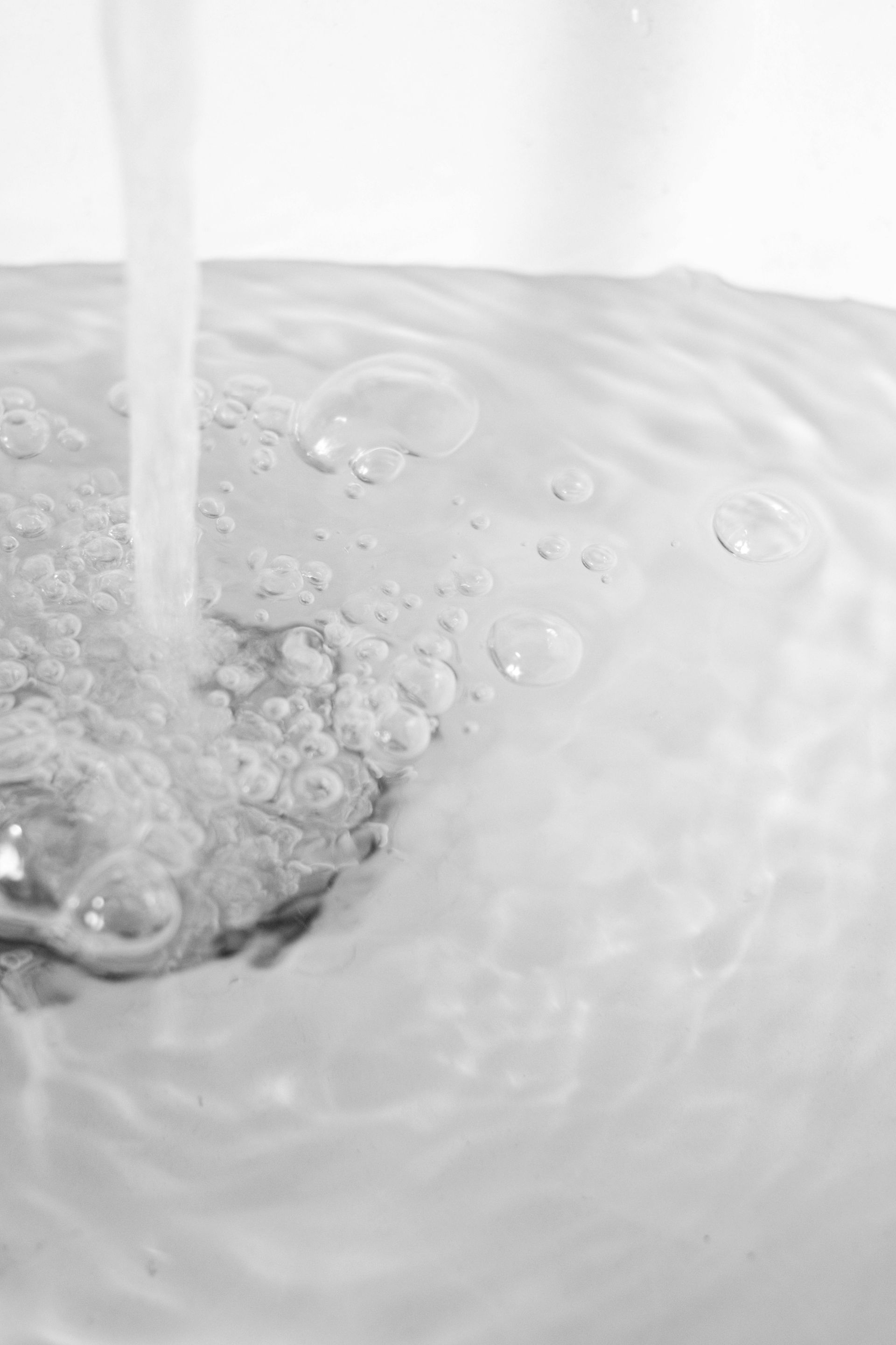Water pouring into a sink, creating bubbles and swirling water.