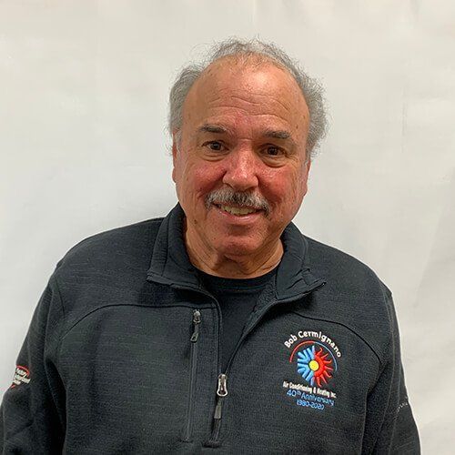 A man with a mustache is wearing a black jacket and smiling.