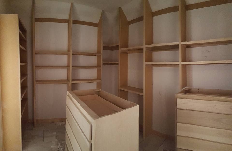 A walk in closet with lots of shelves and drawers