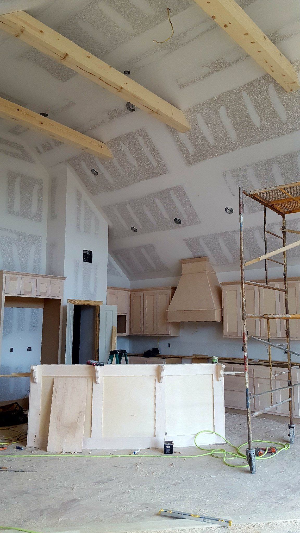 A kitchen under construction with a vaulted ceiling and wooden beams.