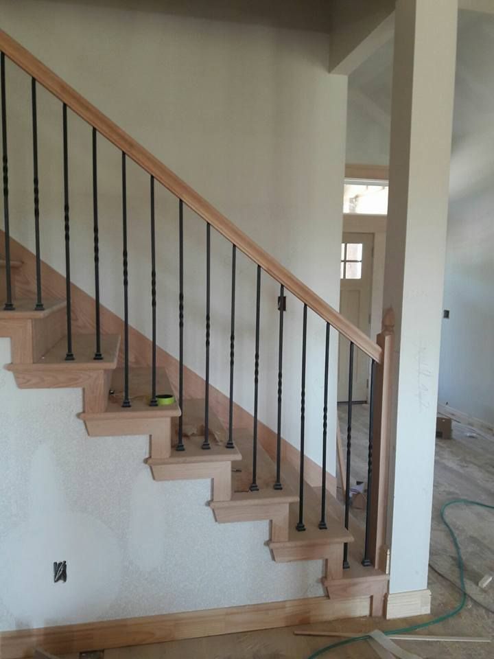 A wooden staircase with a metal railing is being built in a house.
