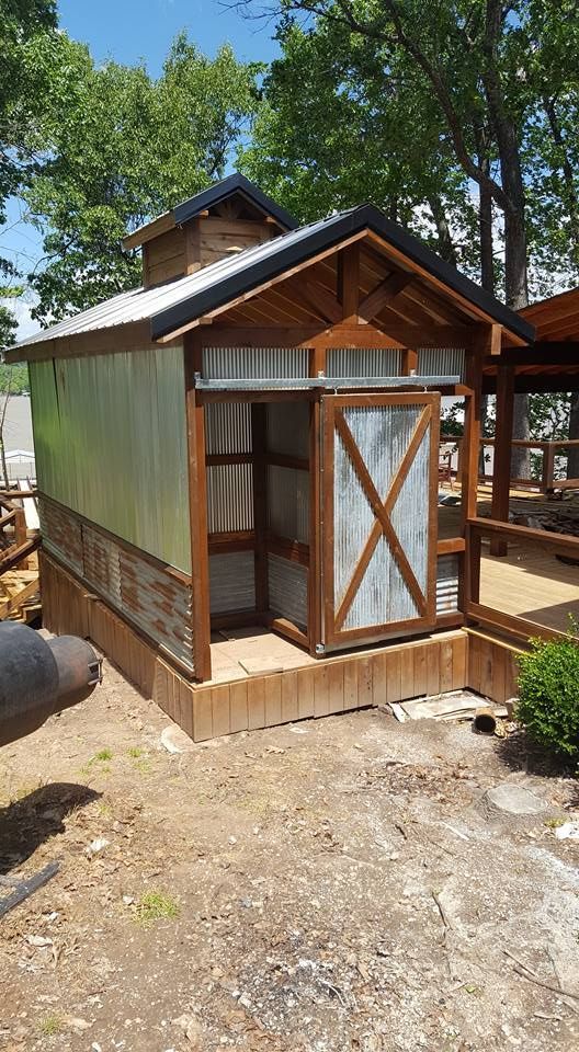 A small wooden shed with a sliding door is sitting on top of a dirt field.