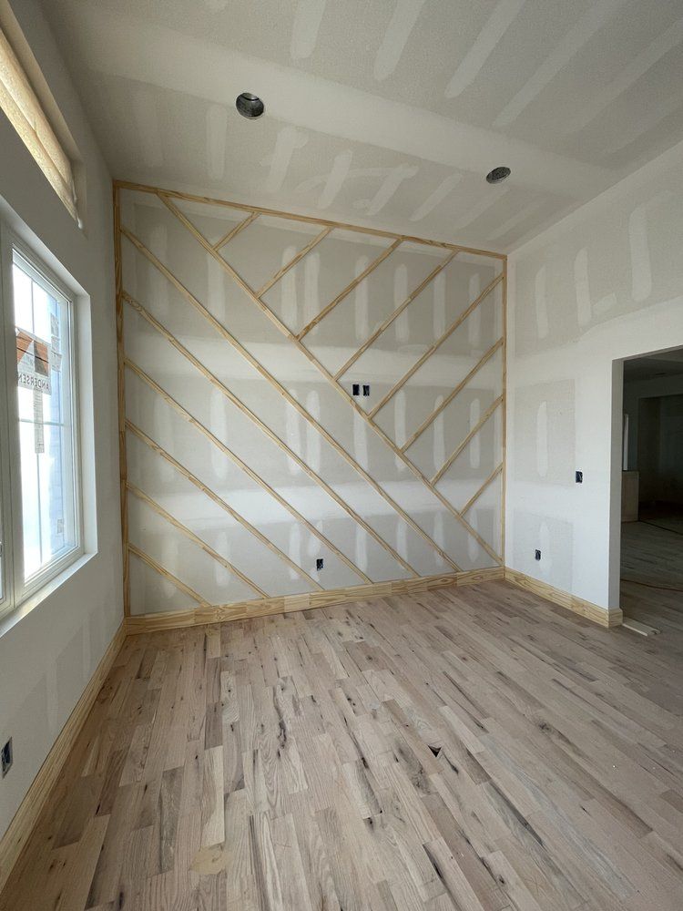 An empty room with a wooden floor and a white wall