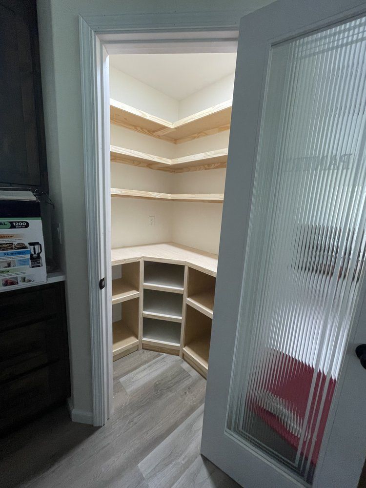 A walk in closet with shelves and a glass door.