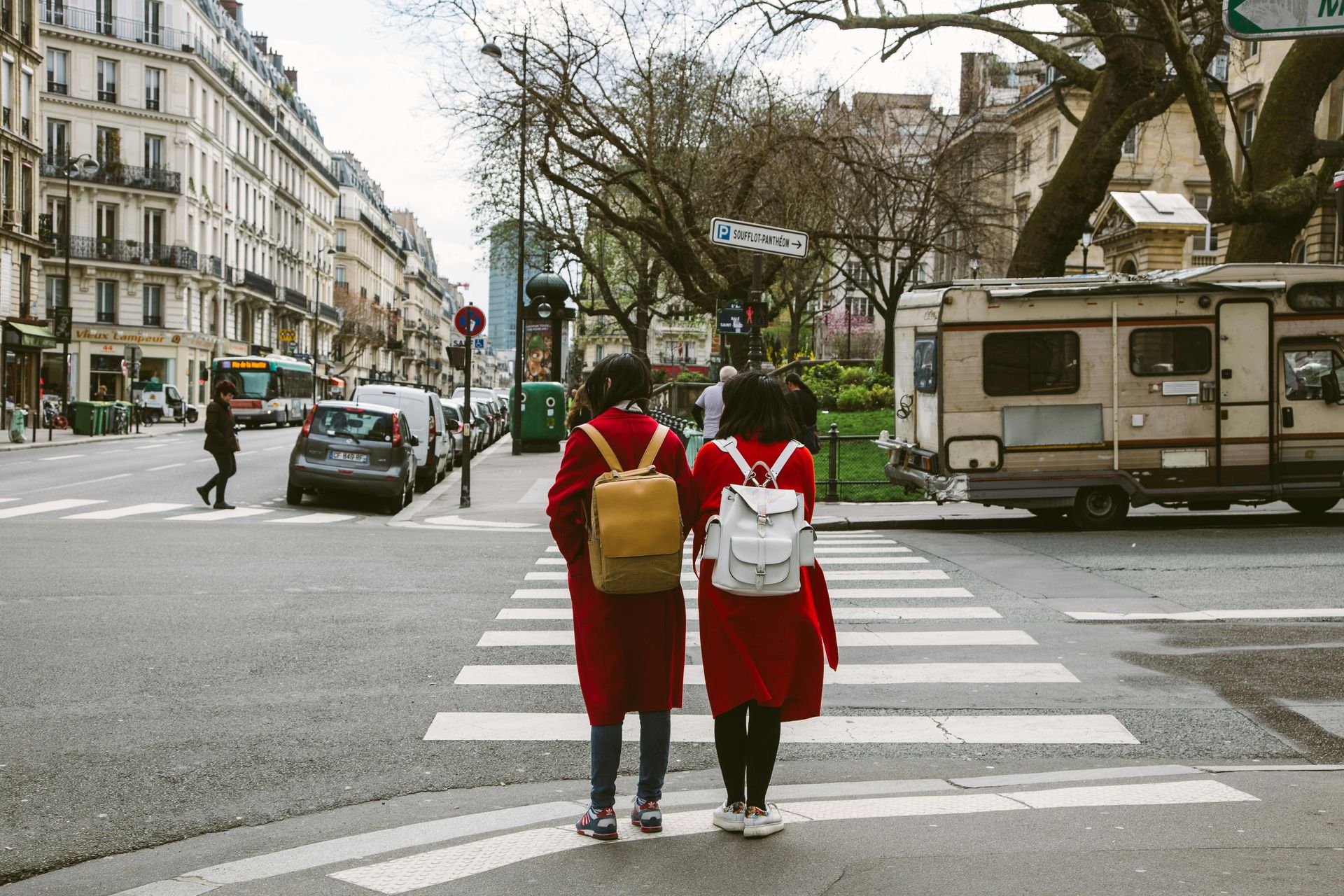 Two women with backpacks are walking across a street.