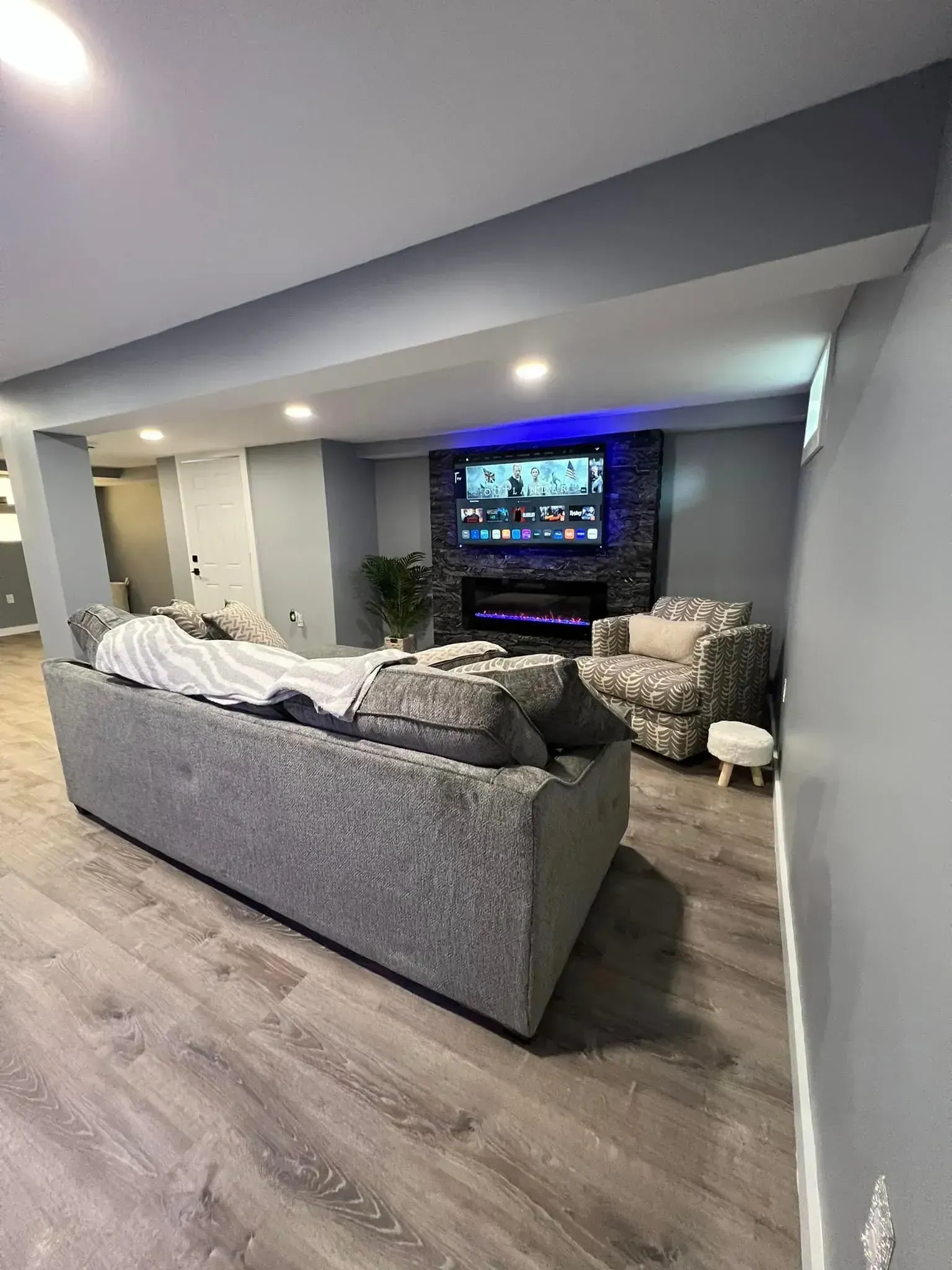 A living room with a couch , chair , television and fireplace.