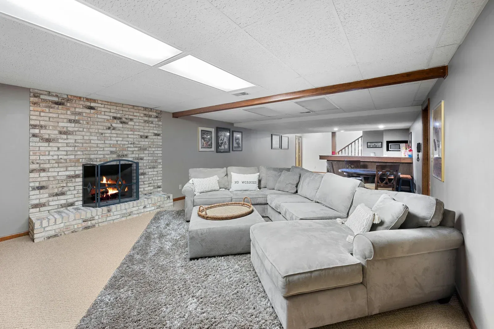 Cozy living room with fireplace, gray sectional sofa, and exposed beam ceiling.