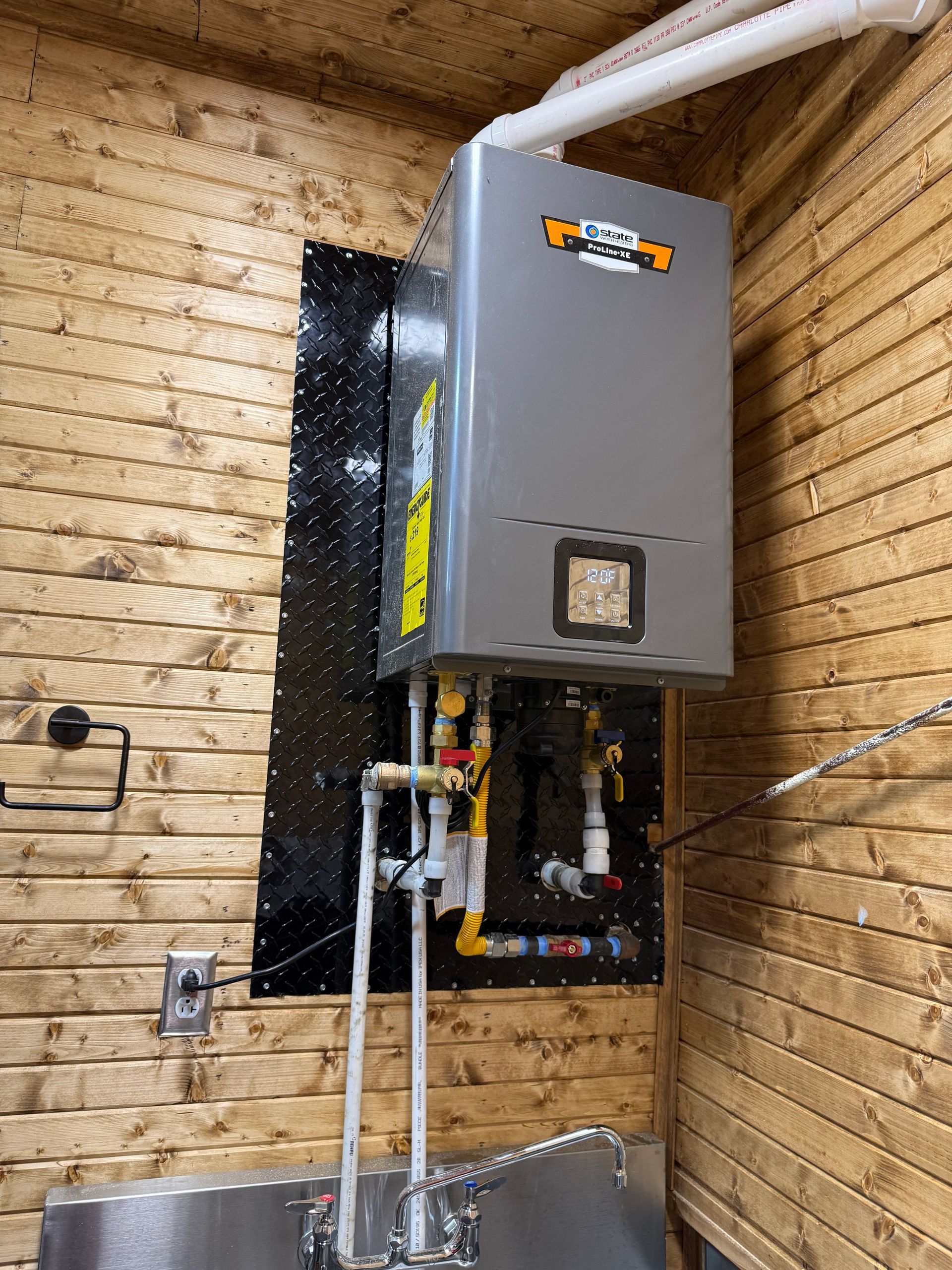 Gray wall-mounted water heater above a utility sink in a tiled laundry or utility room