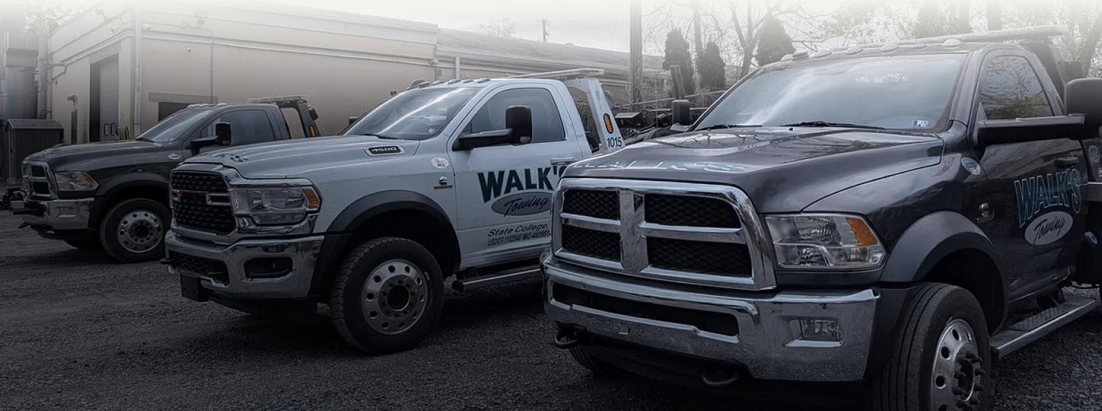 Three tow trucks parked outside. | Walk's Towing