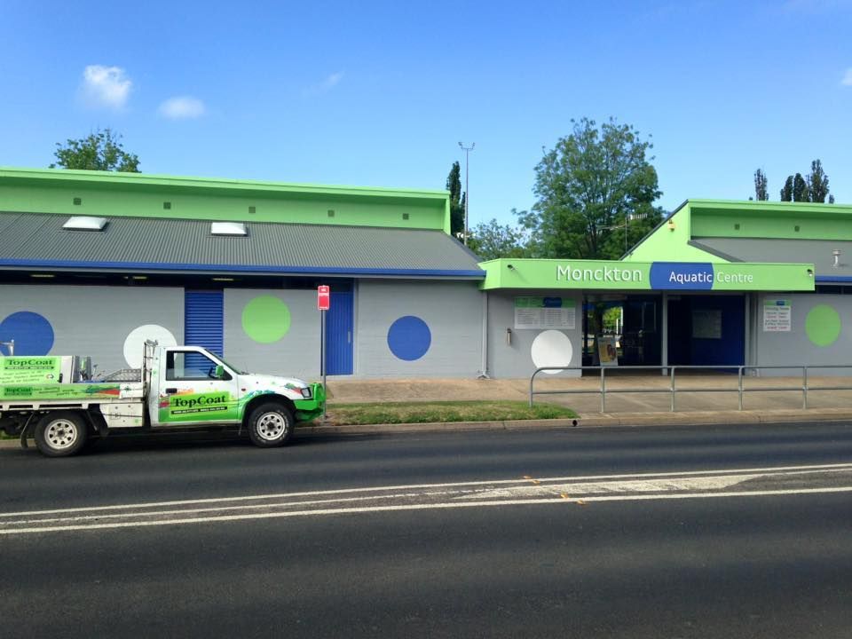 A green and white truck is parked in front of a building