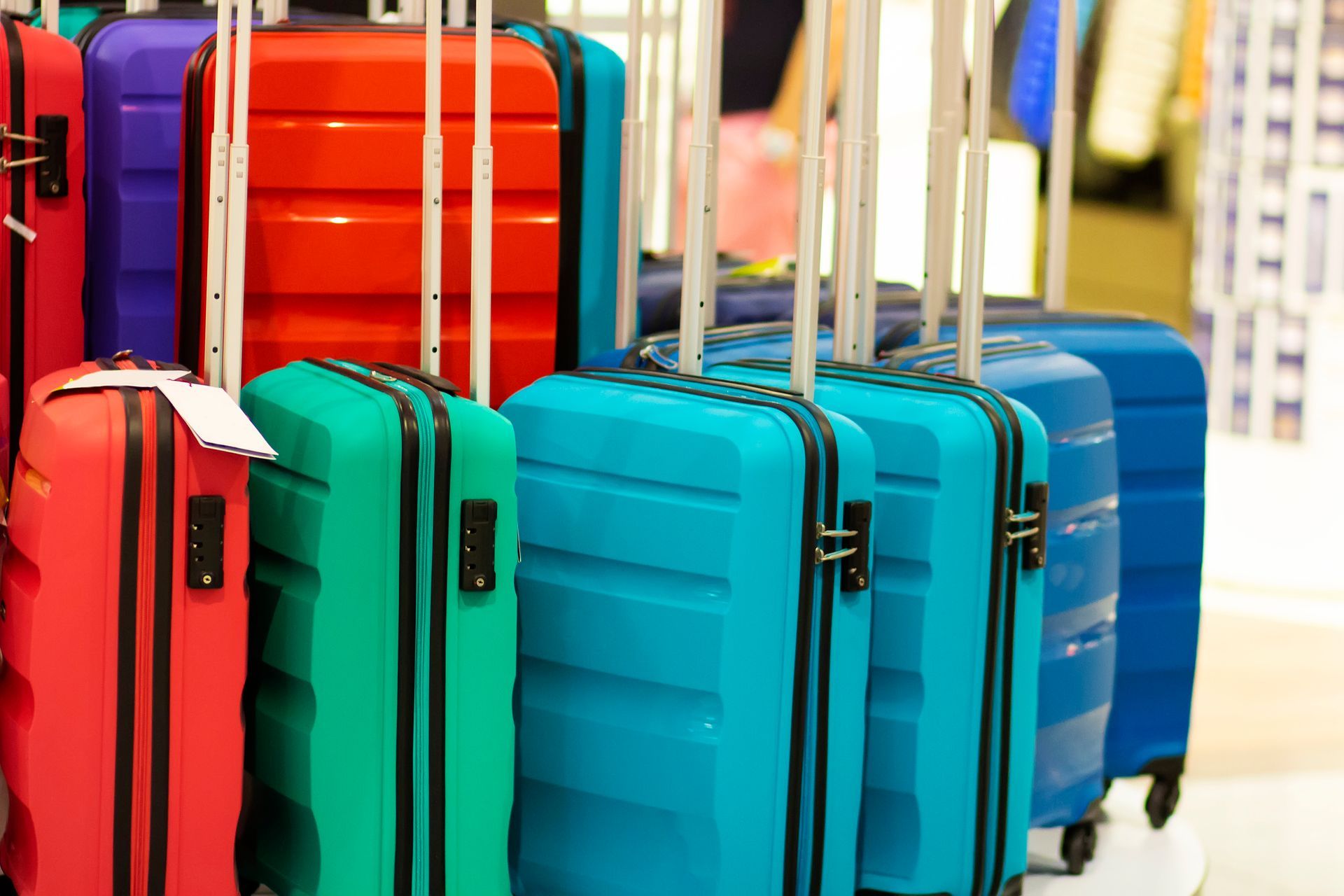 A row of colorful suitcases are lined up on display in a store.
