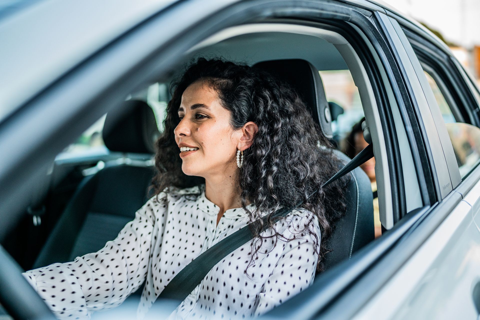 A smiling woman is driving a car, showcasing reliable auto insurance. A smiling woman is driving a car, showcasing reliable auto insurance.